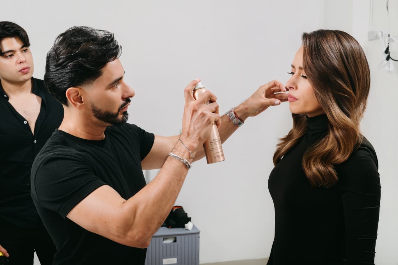 Sebastián Guzmán fijando con spray el peinado en ondas de una modelo